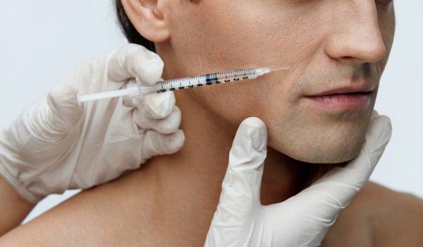 Male Beauty Injection. Portrait Of Handsome Man Receiving Hyaluronic Acid Facial Injections. Closeup Of Cosmetician Injecting Fillers Into Young Man's Face. Plastic Surgery Conceprt. High Resolution